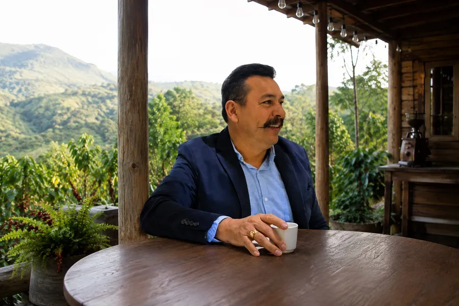 Francisco Amadeo Palencia Rivas, fundador de Finca El Cascajal, con una taza de café en el corredor de la finca frente al cafetal